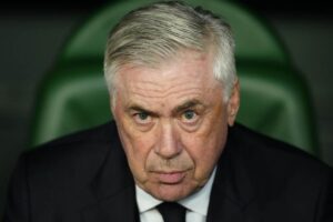 Carlo Ancelotti in primo piano e seduto in panchina
