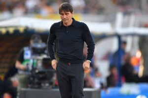 Antonio Conte in piedi, con gli occhi chiusi e le mani in tasca