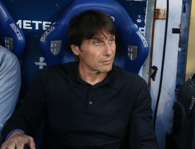 Antonio Conte in primo piano, seduto in panchina e con sguardo di lato