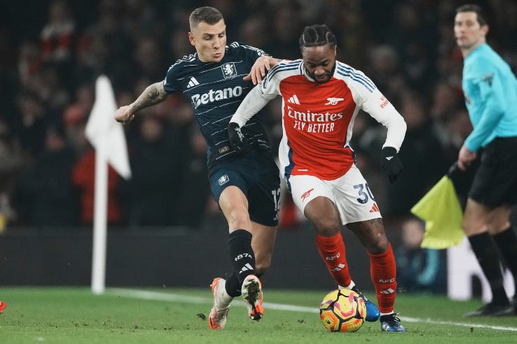 Raheem Sterling palla al piede e contrastato da un avversario